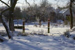 Dřevěné sloupy (pozůstatek staré ohrady pro koně) natřené na červeno kontrastují se sněhovou pokrývkou.